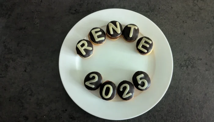 Auf einem Teller sind glasierte Plätzchen angeordnet mit dem Schriftzug "Rente 2025"