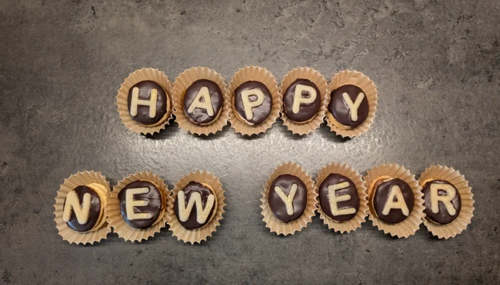 Plätzchen mit Buchstaben aus Zuckergussschrift zusammengelegt zu dem Satz "Happy New Year"